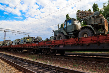 Fototapeta na wymiar Cargo train carrying military vehicles on railway flat wagons