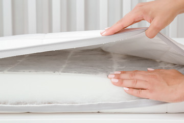 Woman hands touching different layers of new white mattress. Foam rubber and buckwheat inside....