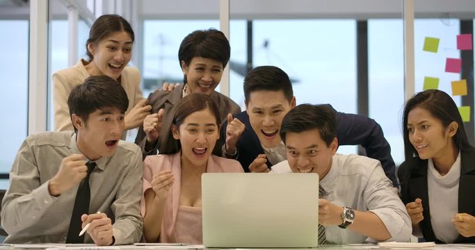 Happy diverse casual creative business team are working hard to complete a business deal. They celebrate when they discover that they have been successful.