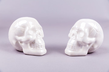 White shiny ceramic skull figures on a blank background