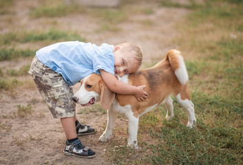 A boy with Down syndrome plays in the playground. Genetic disease in a child. Toddler hugs a dog.