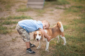 A boy with Down syndrome plays in the playground. Genetic disease in a child. Toddler hugs a dog.