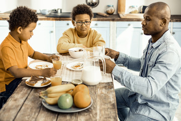 Dad and his son trying to persuade the older one to having breakfast.