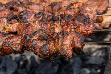 Grilled kebab cooking on metal skewer closeup. Roasted meat cooked at barbecue. BBQ fresh beef meat chop slices. Traditional eastern dish, shish kebab
