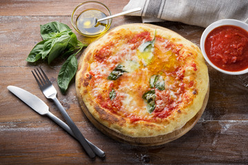 Pizza margherita and ingredients on wood background
