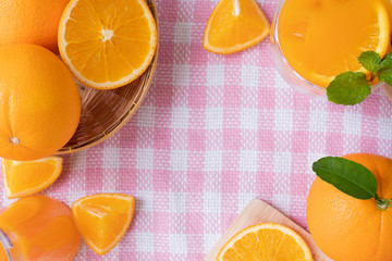 Frame for text with sliced orange fruit on pink tablecloth texture background, view from above table.