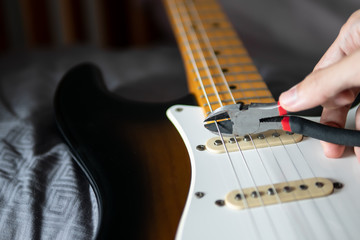Cutting electric guitar string with cutter. Restringing guitar.