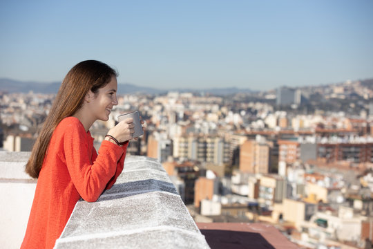 Chica adolescente feliz tomando un caf&eacute; en la azotea