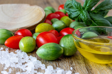 pomodorini verdi e rossi con olio cristalli di sale e basilico su fondo legno