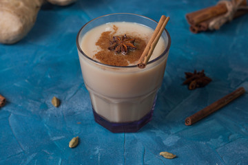 Traditional indian drink - masala tea with spices on a blue background, horizontal orientation.