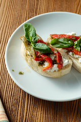 bruschetta with bell pepper, basil, pesto sauce and mozzarella on a white plate on a wooden background. Italian restaurant. Top view food photo