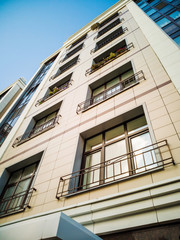 Beige-brown facade of a multi-storey building in a classical style with a beautiful window decor. Housing concept, design of residential buildings.