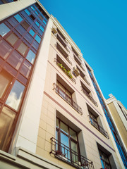 Beige-brown facade of a multi-storey building in a classical style with a beautiful window decor. Housing concept, design of residential buildings.