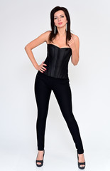 Fototapeta premium Full-length vertical portrait of a sexy brunette woman in black clothes on a white background. It is in different poses. Great makeup and beautiful hair.