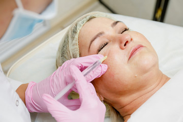 Beautician doing facial injection. Anti-aging revitalization cosmetology procedure