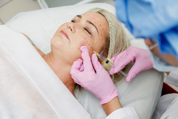 Obraz na płótnie Canvas Beautician doing facial injection. Anti-aging revitalization cosmetology procedure