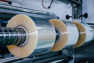 roll of plastic packaging film on the automatic packing machine in food product factory. industrial and technology concept.