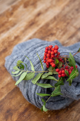 Red rowan on the wooden background with woolen knitted