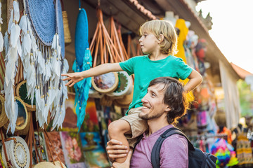 Dad and son at a market in Ubud, Bali. Typical souvenir shop selling souvenirs and handicrafts of...