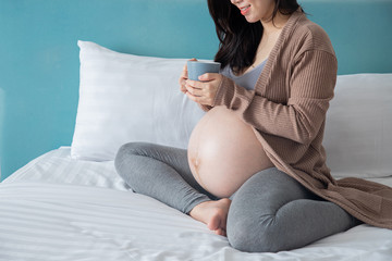 pregnancy, motherhood and expectation concept - smiling pregnant woman drink some milk.