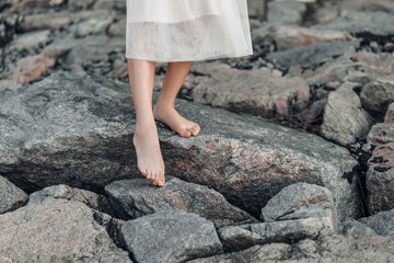 Woman feet with pastel pedicure standing on the stones.