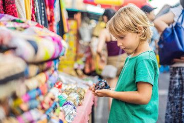 Boy at a market in Ubud, Bali. Typical souvenir shop selling souvenirs and handicrafts of Bali at the famous Ubud Market, Indonesia. Balinese market. Souvenirs of wood and crafts of local residents