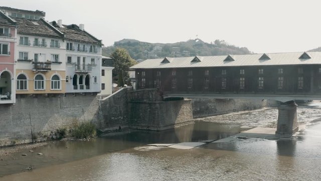 Aerial pan reveal of Lovech covered wooden bridge Bulgaria by architect Kolyu Ficheto over the Osam river and ancient fortress on Hisarya hilltop.