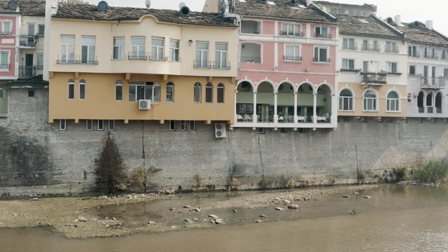 Eye level pan reveal of Lovech covered wooden bridge Bulgaria by architect Kolyu Ficheto over the Osam river and ancient fortress on Hisarya hilltop.