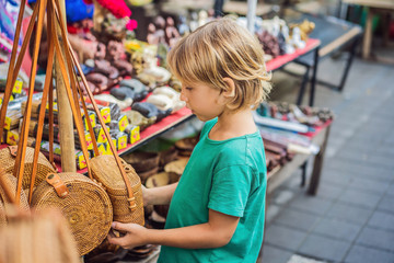 Boy at a market in Ubud, Bali. Typical souvenir shop selling souvenirs and handicrafts of Bali at the famous Ubud Market, Indonesia. Balinese market. Souvenirs of wood and crafts of local residents
