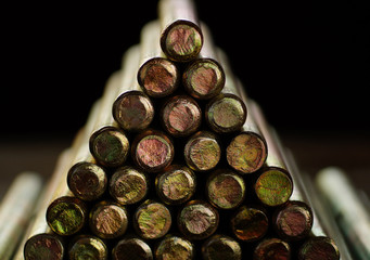 Metal parts with a shiny butt, cylindrical shape, folded slide in the shape of a triangle closeup on a black background.