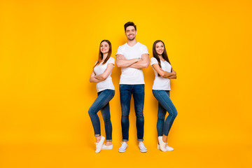 Naklejka premium Full length photo of lovely hipsters crossing their arms smiling wearing white t-shirt denim jeans isolated over yellow background