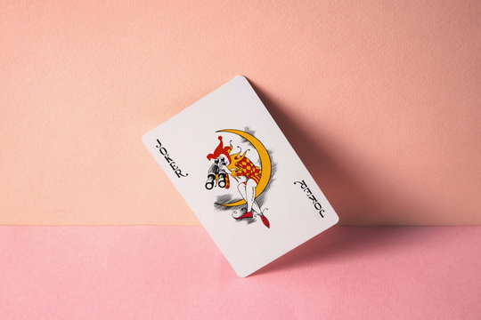Joker playing card on pink background.