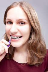 Dental Concepts. Closeup Portrait of Teenage Girl Using Bristle Brush for Cleaning Braces and Teeth.