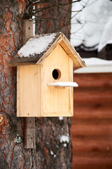 empty nailed wooden birdhouse on the tree under the snow.