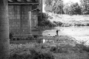 black and white photo with a man standing under the bridge