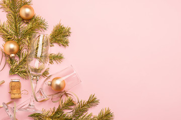 New Year or Christmas layout balls glass goblet branch spruce serpentine cork from bottle of gold color pink background.