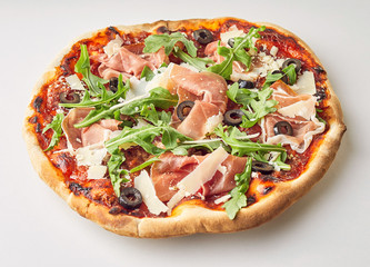 Tasty prosciutto, rocket and olive Italian pizza