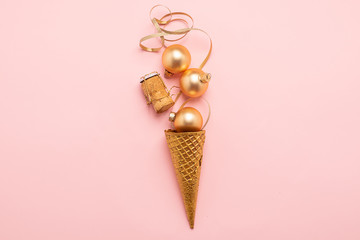 Ice cream waffle cup Christmas balls serpentine cork from a bottle of gold color on a pink background. New Year concept.