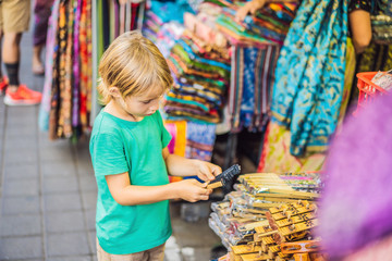 Boy at a market in Ubud, Bali. Typical souvenir shop selling souvenirs and handicrafts of Bali at the famous Ubud Market, Indonesia. Balinese market. Souvenirs of wood and crafts of local residents