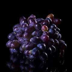 Bunch of grapes on a black background with water drops.