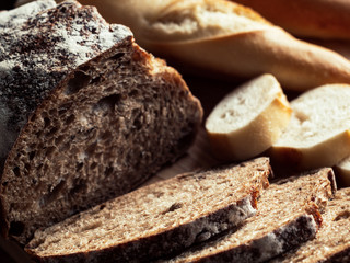 Fresh baked rye bread and sliced bread on rustic wooden board. Closeup.
