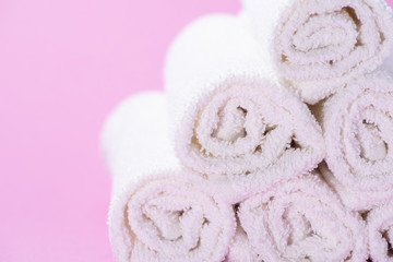 Obraz na płótnie Canvas Gently rolled terry towels for spa or massage on a pink background