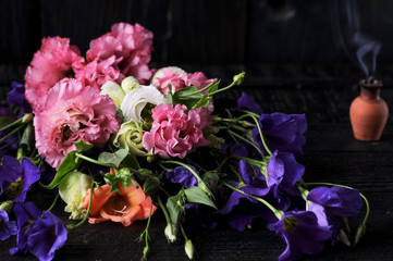 a bouquet of flowers on a black background in the background a small glechik with smoke
