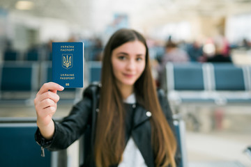 Young happy woman holding Ukraine passport in terminal of airport