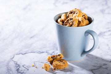 Chocolate chip cookies in blue cup on marble stone background. Selective focus. Copy space.