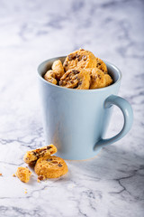 Chocolate chip cookies in blue cup on marble stone background. Selective focus. Copy space.