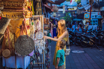 Mom and son travelers choose souvenirs in the market at Ubud in Bali, Indonesia