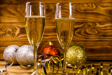 Two wineglasses with champagne and different christmas decorations on wooden table