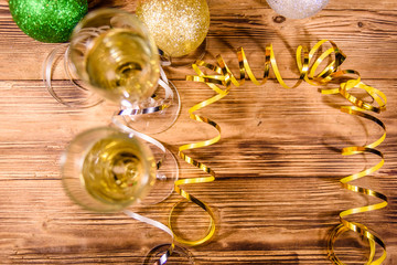 Two wineglasses with champagne and different christmas decorations on wooden table. Top view