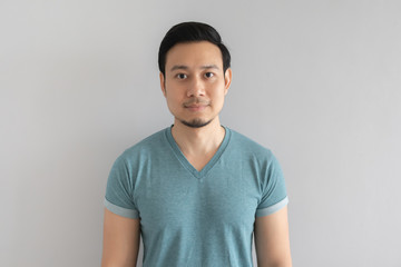 Normal straight face portrait of man in blue t-shirt on grey background.
